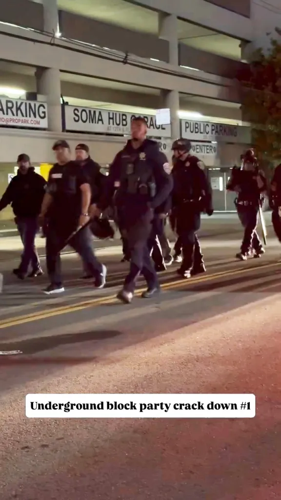 Police officers walking down a street in front of a parking garage.