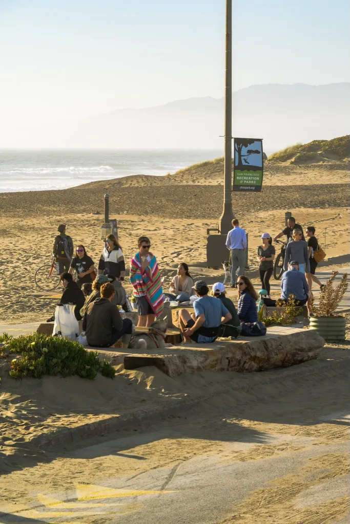 People gather on the beach near the Great Highway, now known as Sunset Dunes, with the ocean in the background.