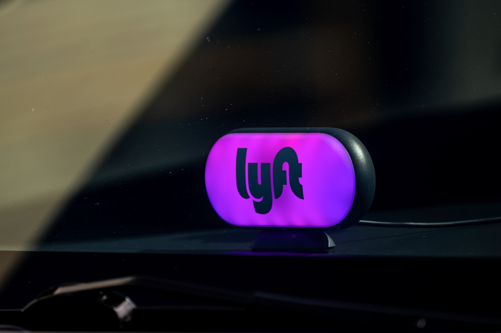 A Lyft sign with its logo, illuminated in purple, on a vehicle dashboard.