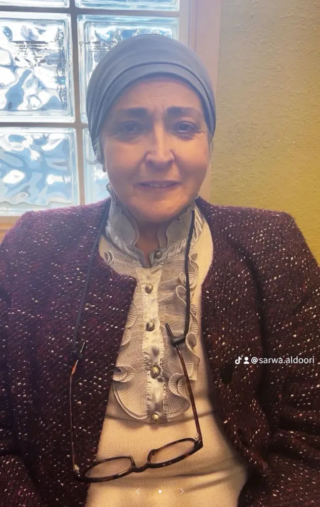 Sarwa Aldoori wearing a headscarf, a ruffled white blouse, and a tweed jacket.