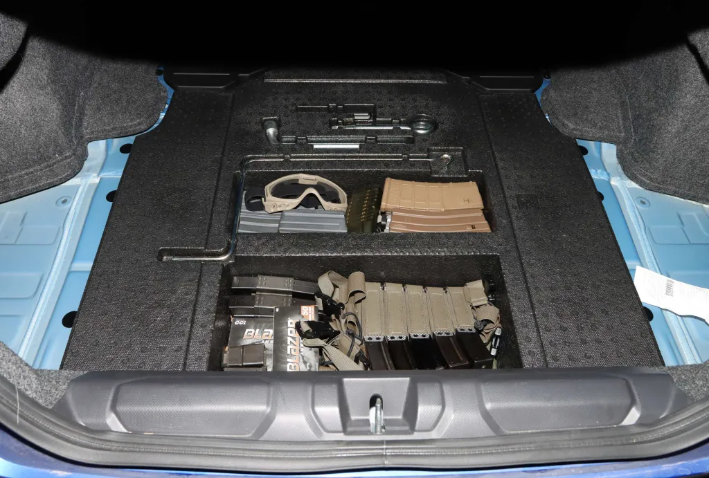 Car trunk showing ammunition, magazines, tactical gear, and tools.