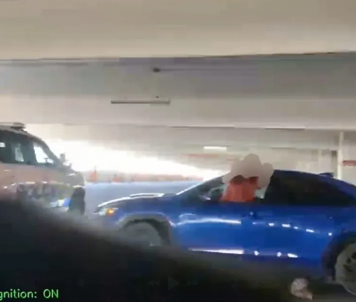 A blue car with a white cowboy hat sticker on the driver's head is being stopped by a police vehicle.