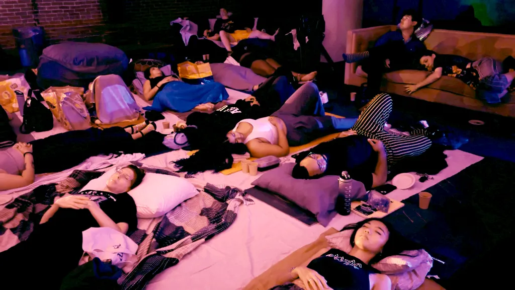 People lying on blankets and pillows on the floor, some asleep or relaxing.