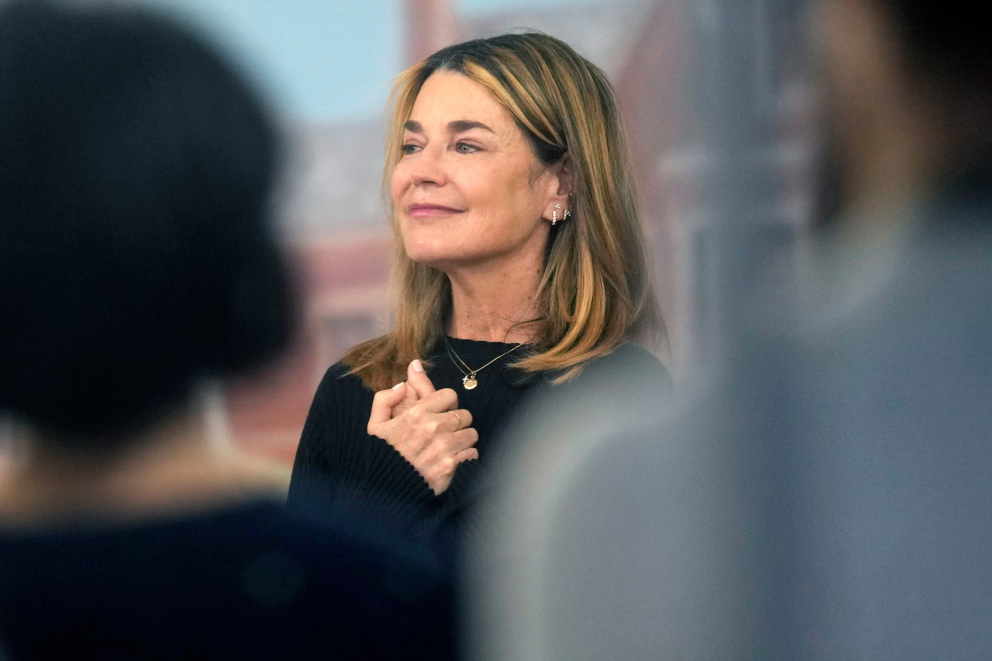 Savannah Guthrie in a black sweater, with her hands clasped, looking slightly up and to the right.