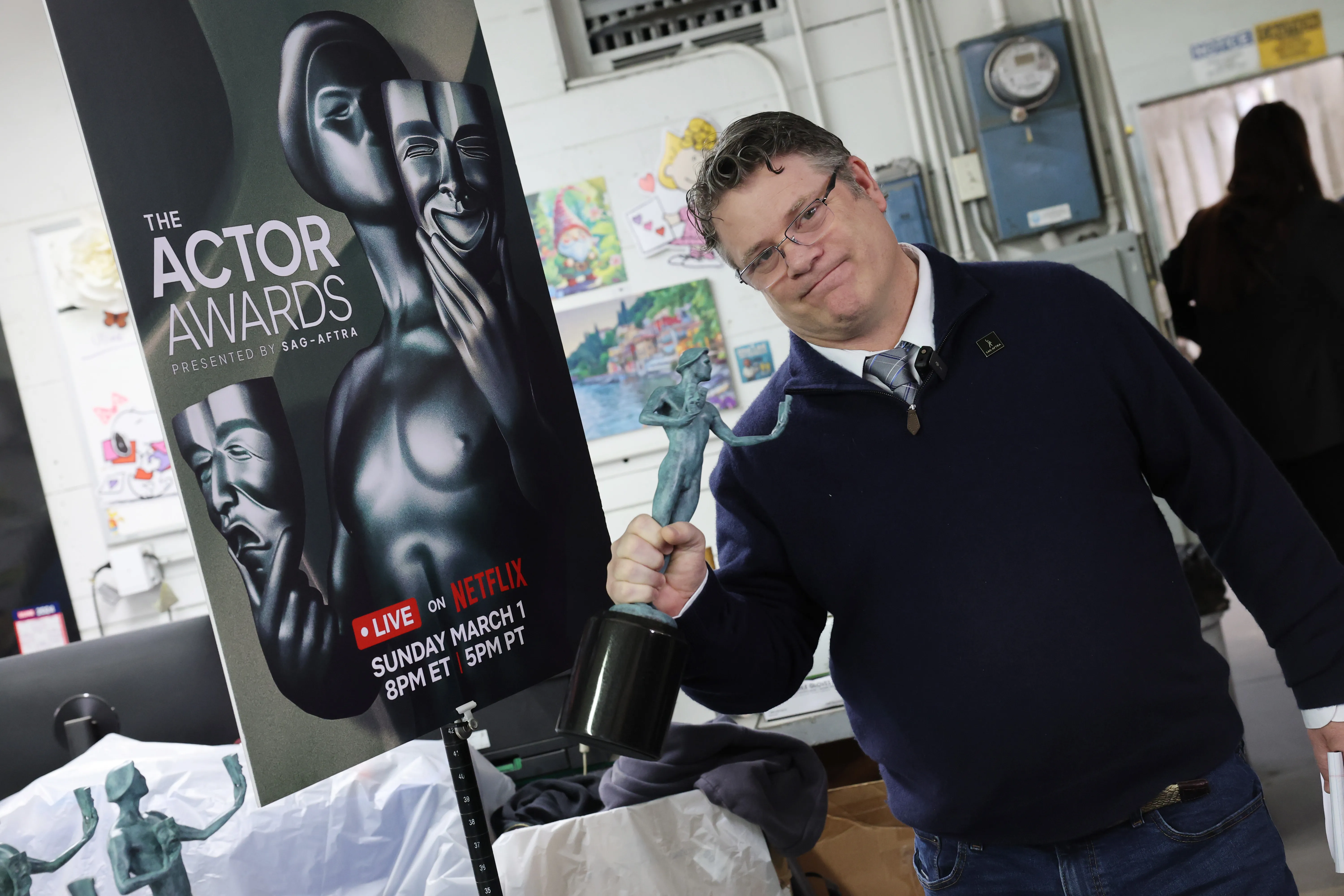 Sean Astin holding the Actor Awards statuette next to a banner for the event.