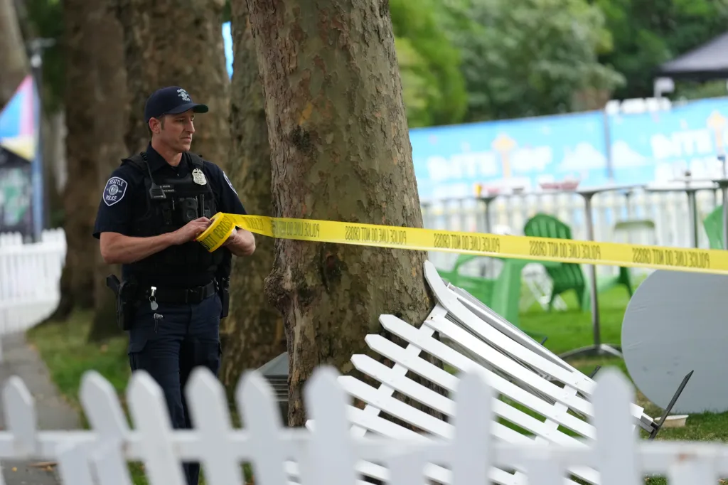 A Seattle police officer sets up yellow "POLICE LINE DO NOT CROSS" tape at the scene of a shooting.