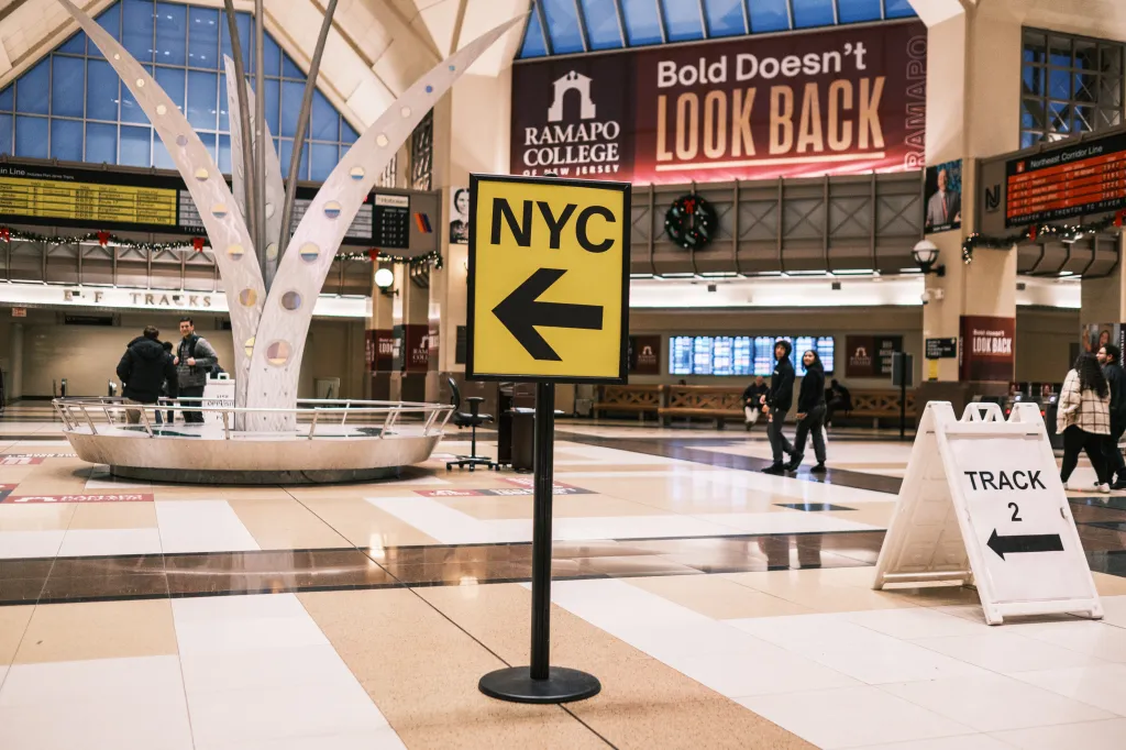 An indoor view of the Frank R. Lautenberg Secaucus Junction with an "NYC" sign pointing left and a "Track 2" sign pointing left.