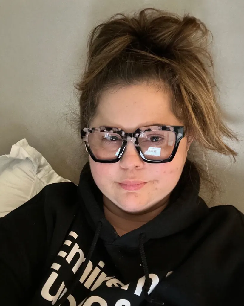 Mandy Teefey wearing a black hoodie and patterned glasses.