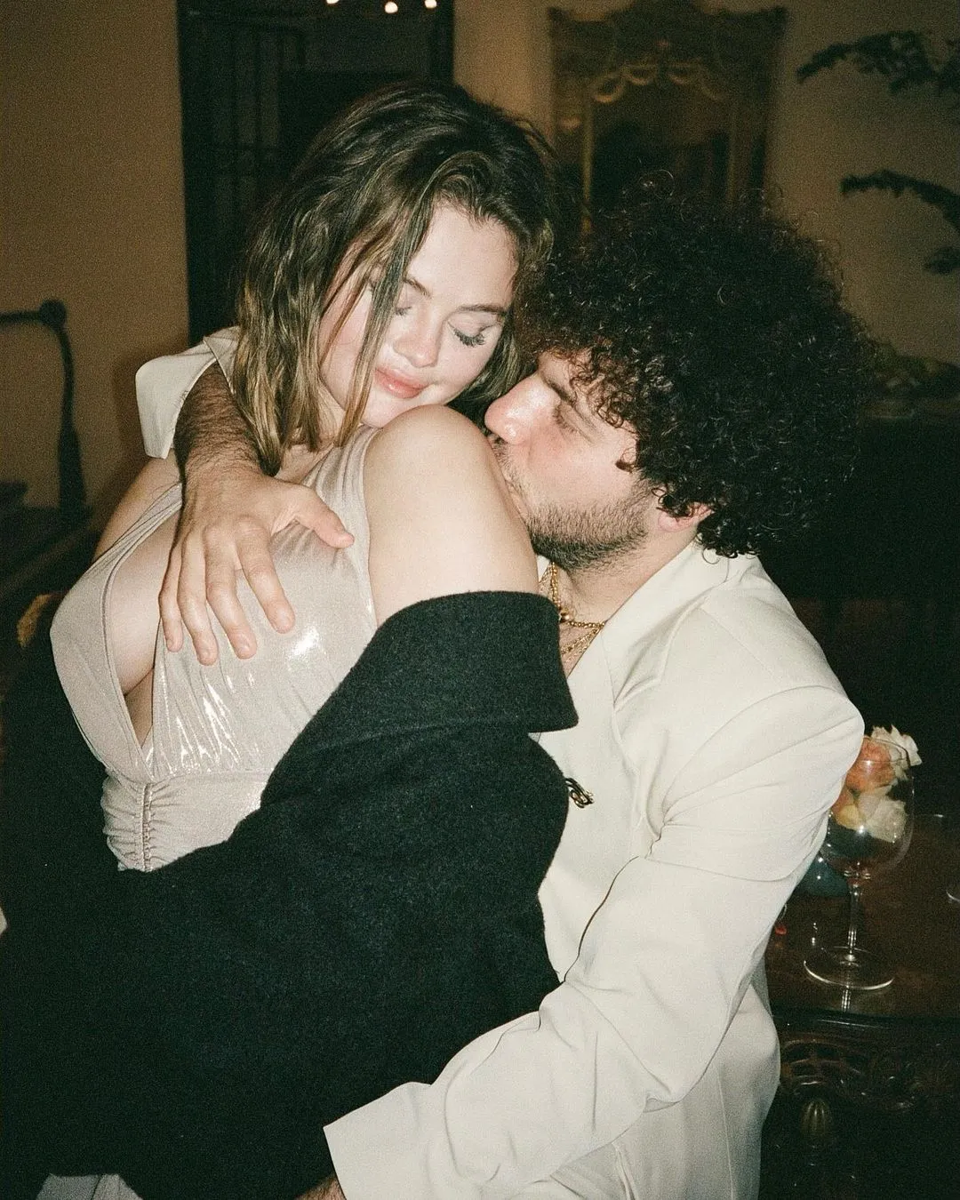 Selena Gomez and Benny Blanco embrace, with Blanco kissing Gomez's shoulder.