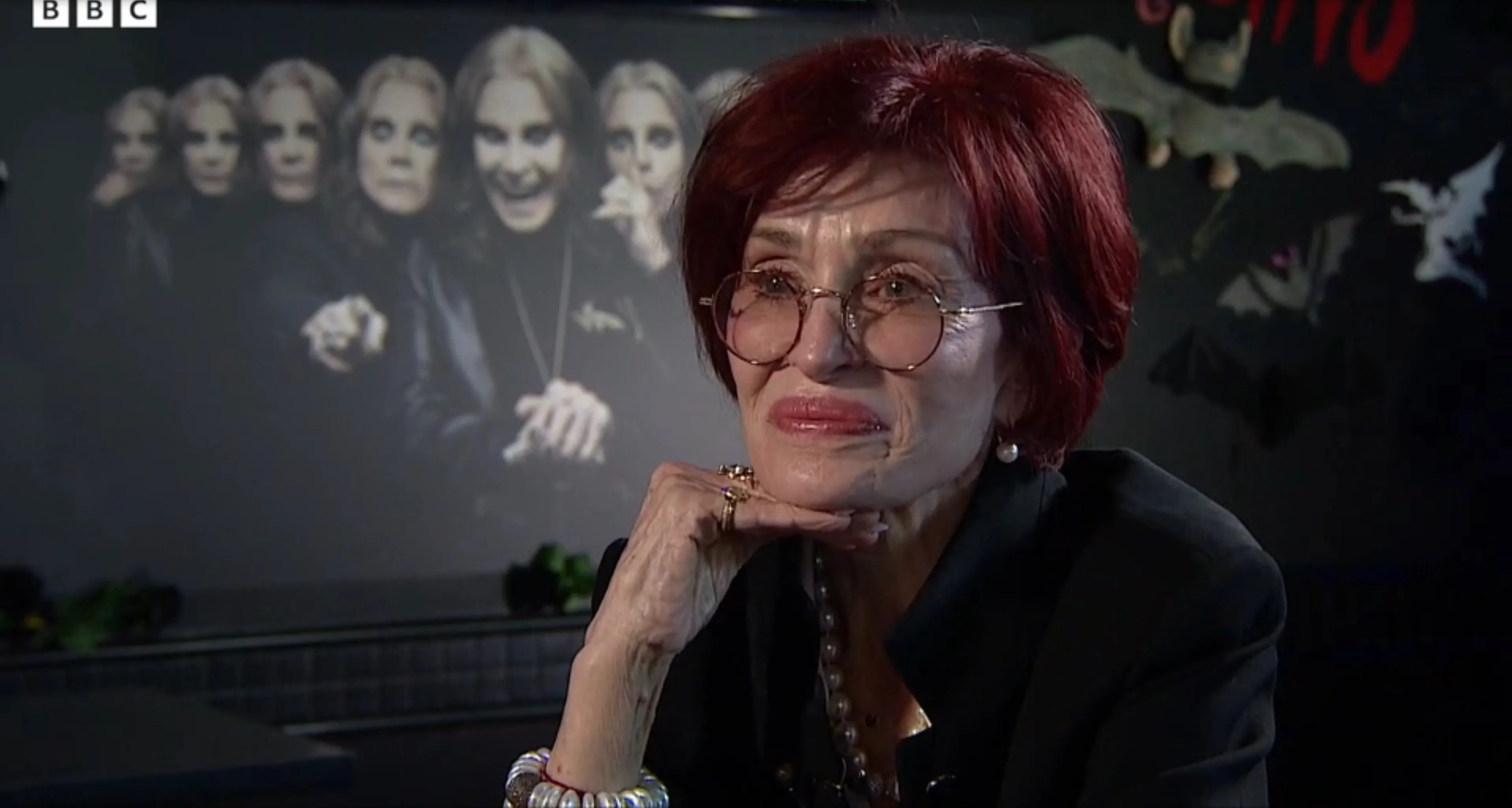 Sharon Osbourne, wearing glasses and a pearl necklace, reflects on Ozzy in an interview.