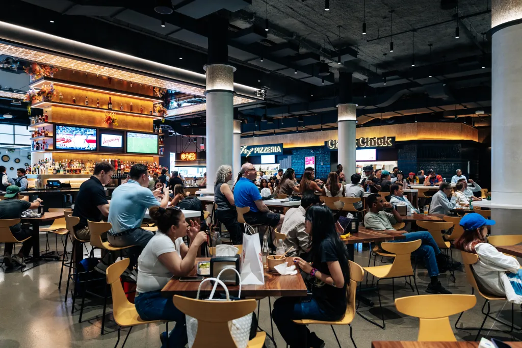 A dining hall at Shaver Hall in Manhattan with people eating and drinking.