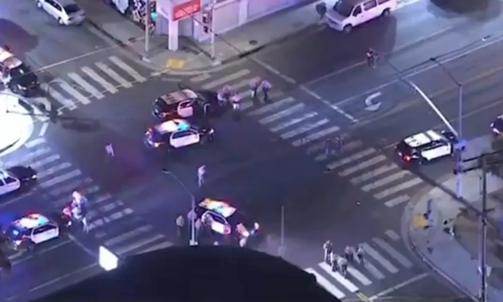 Aerial view of an intersection with multiple police cars and officers investigating a shooting.