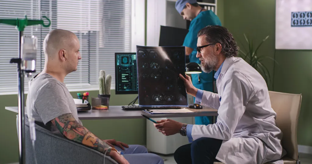 An oncologist shows and explains a CT image to a cancer patient during chemotherapy.