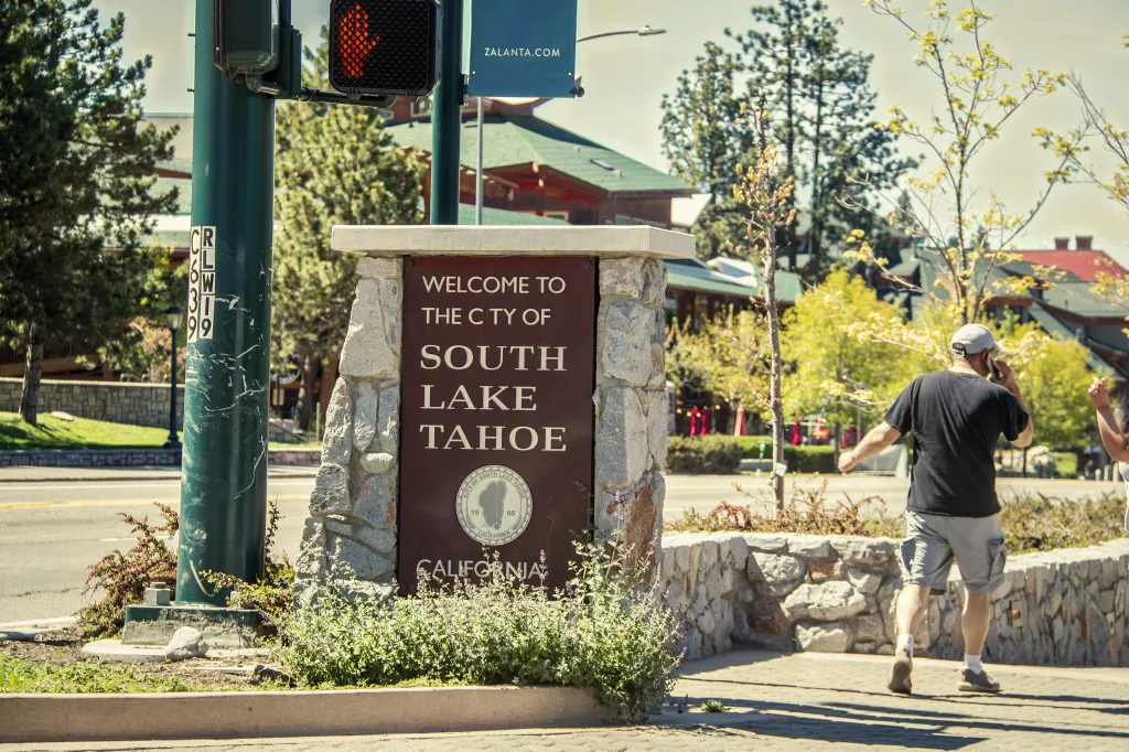 Welcome sign for South Lake Tahoe, California, with a man walking away on the right.