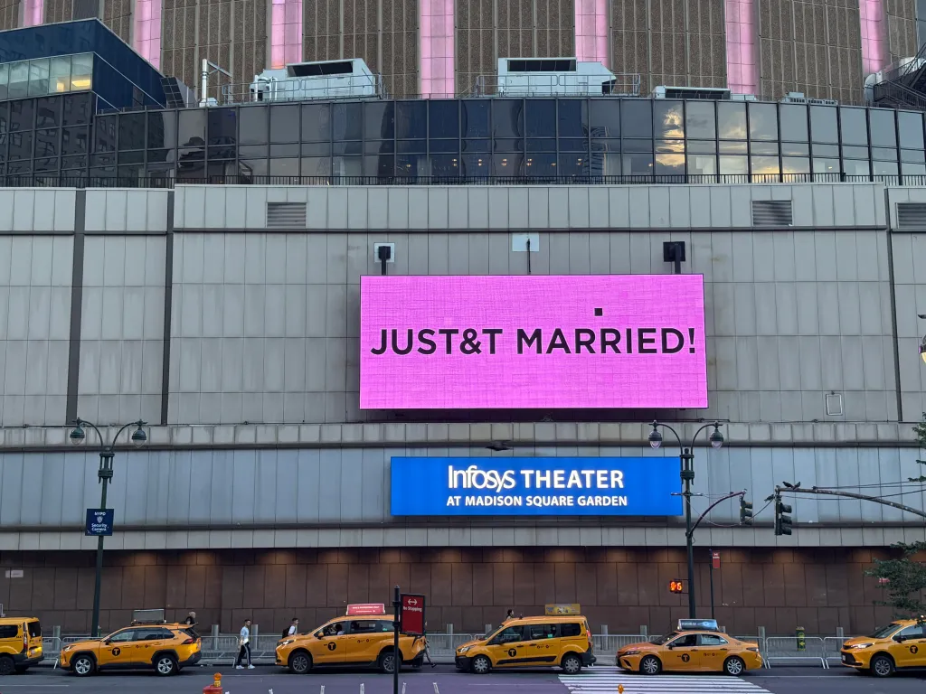 A large pink sign on Madison Square Garden reads "JUST&T MARRIED!" in black letters, while taxis drive past below.