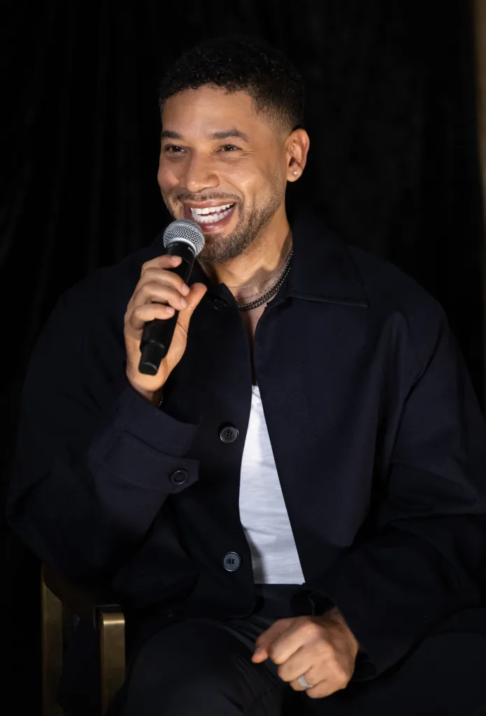 Singer Jussie Smollett speaking on stage, holding a microphone.