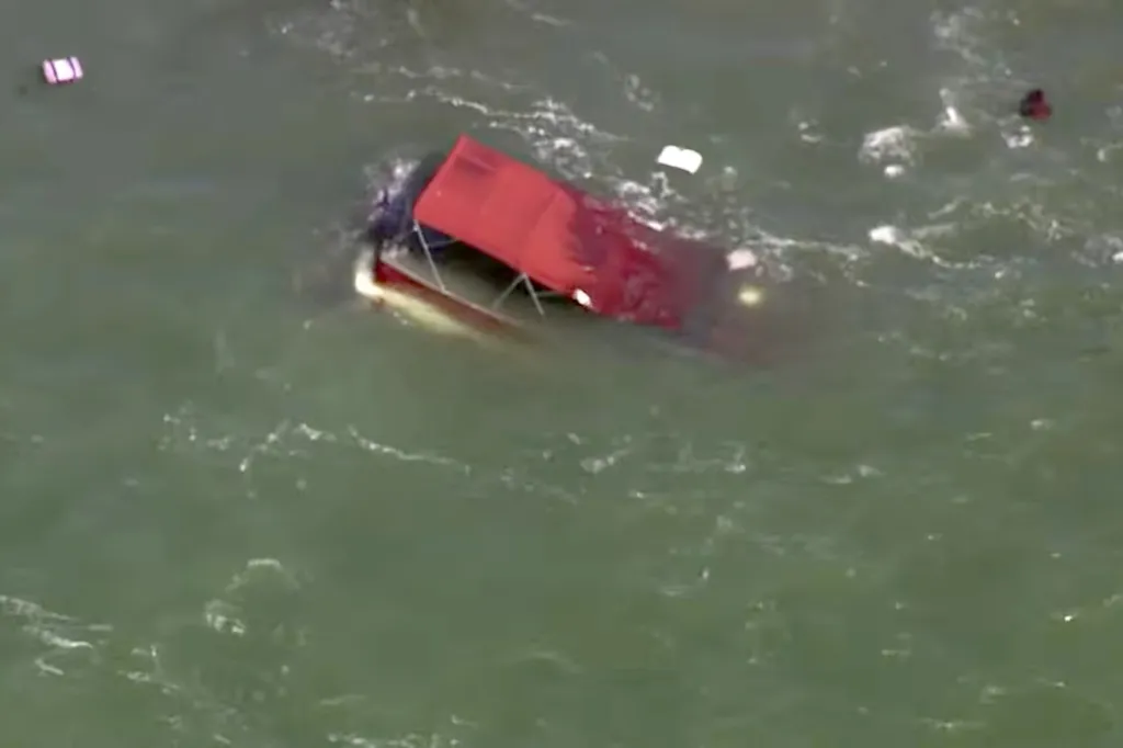 An aerial view of a partially submerged red boat in the water near Alcatraz in San Francisco during a fire and rescue operation.