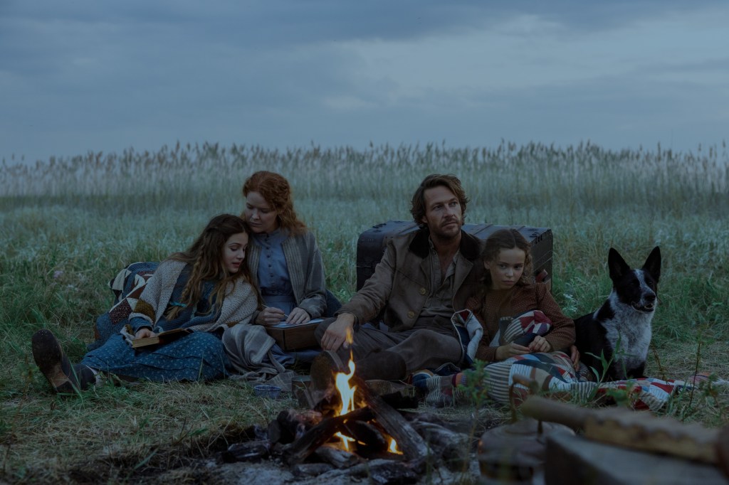 Alice Halsey, Crosby Fitzgerald, Luke Bracey, and Skywalker Hughes sitting around a campfire with a dog in "Little House on the Prairie."