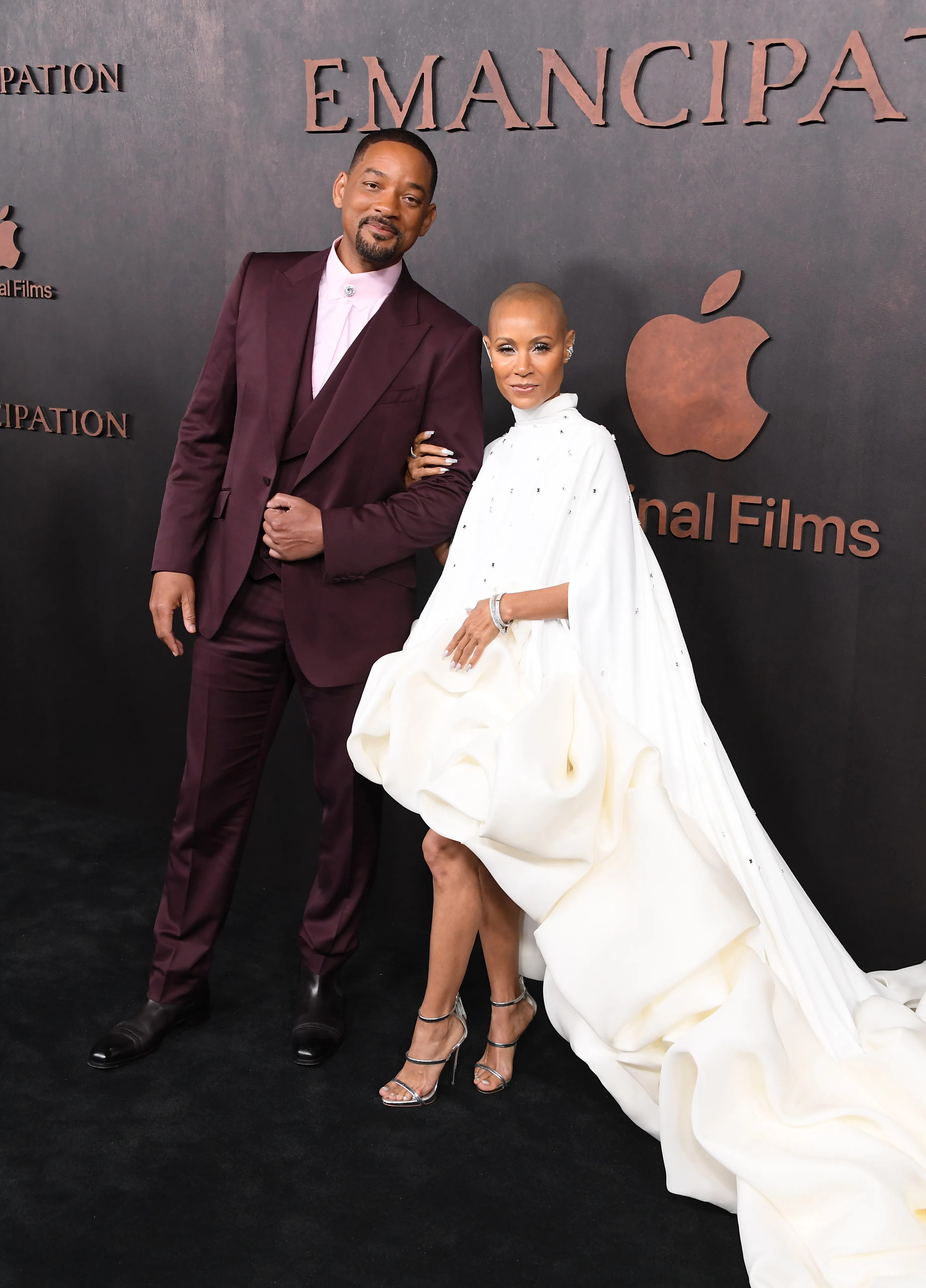 Will Smith and Jada Pinkett Smith posing on a red carpet with "Emancipation" and the Apple logo in the background.