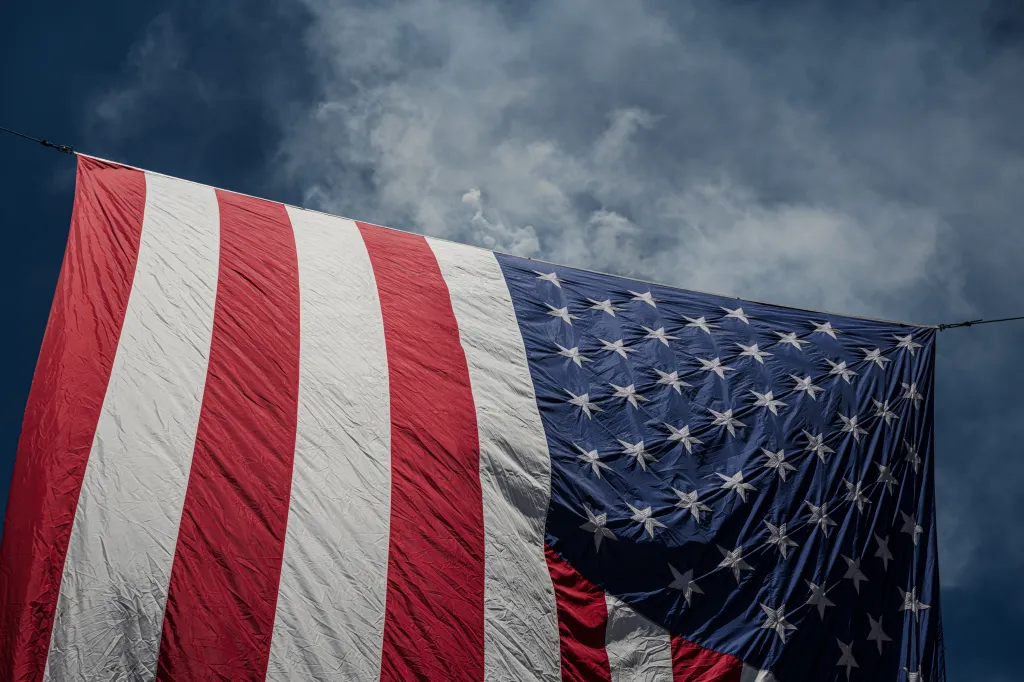 Smoke rises behind an American flag at the "O Say Can You See!" event in Louisville, Kentucky.