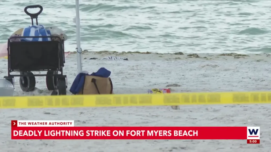 Beach scene with yellow crime scene tape, a wagon, and a beach umbrella, indicating a deadly lightning strike at Fort Myers Beach.