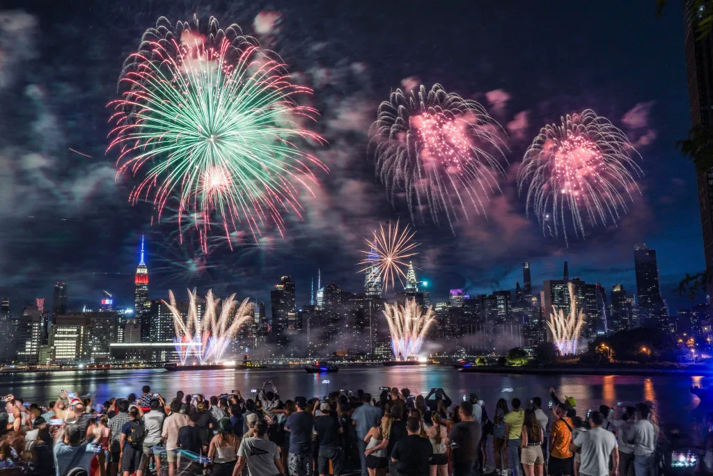 Spectators watch the Macy's fireworks display explode over the Manhattan skyline from Brooklyn.