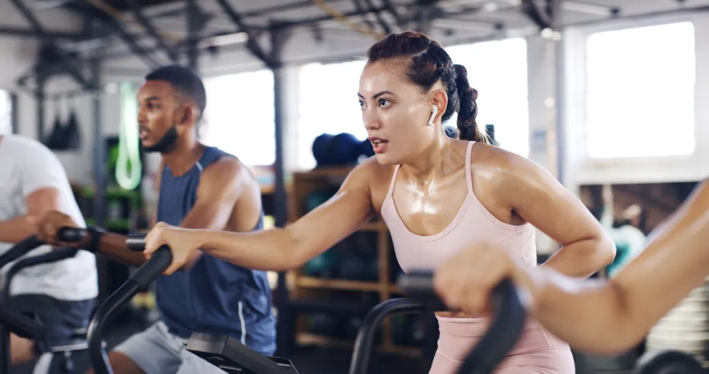 Woman with earphones leading a spin class with other people in a gym.