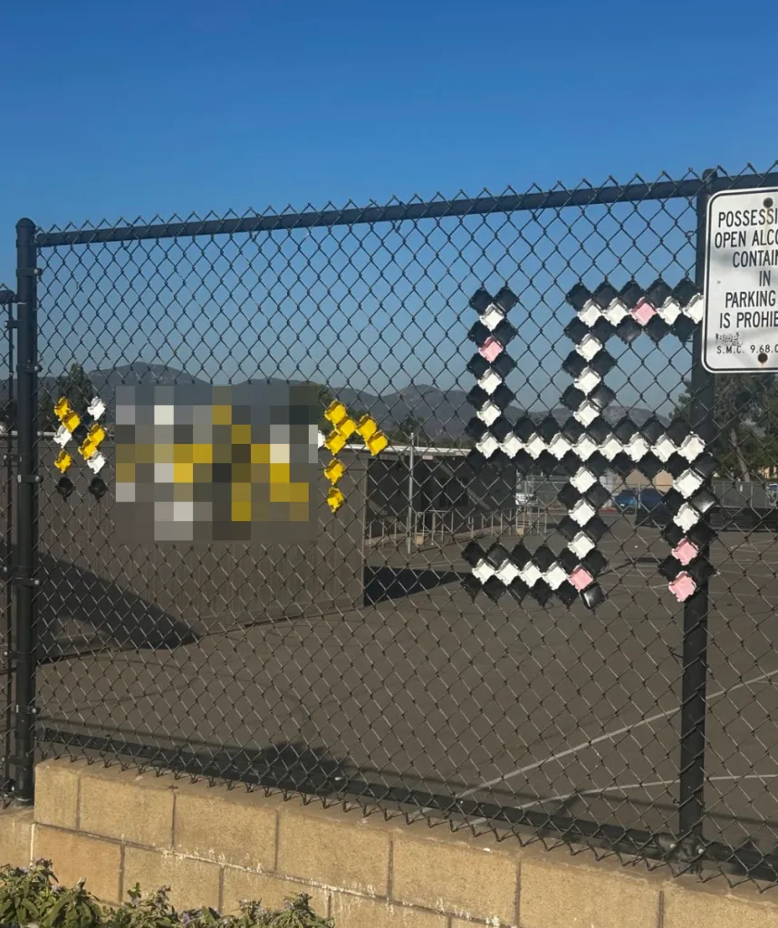 A Nazi symbol and a racial slur made of cups and plates on a fence.