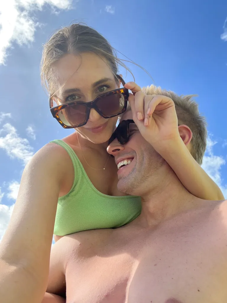 Honeymoon photo of Amanda Batula and Kyle Cooke with Batula on top of Cooke.