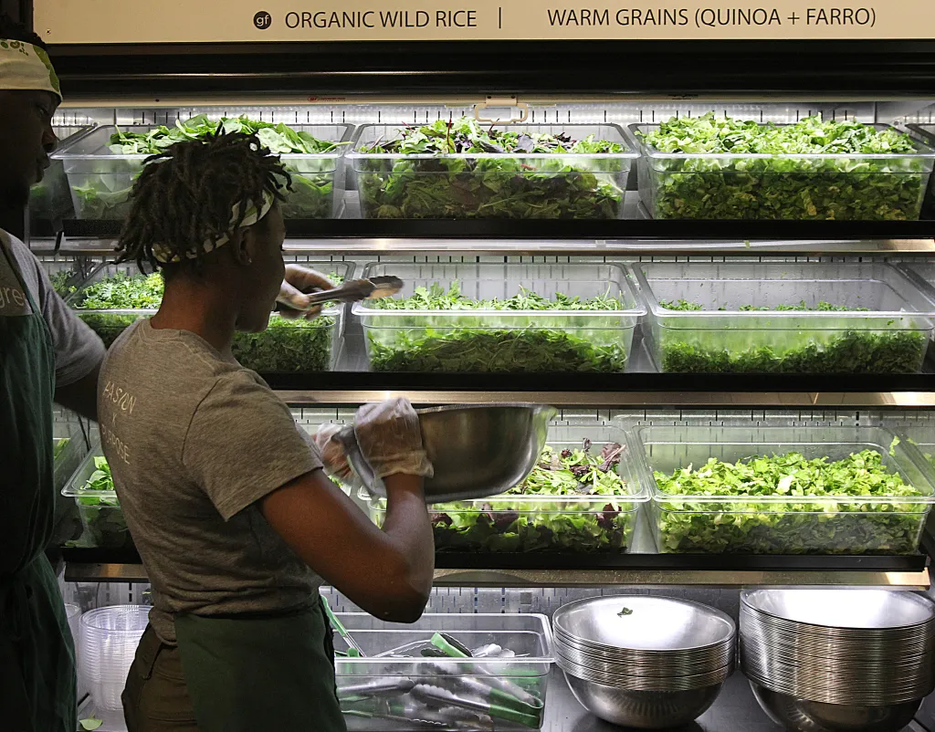 A person preparing a salad at a Sweetgreen restaurant.