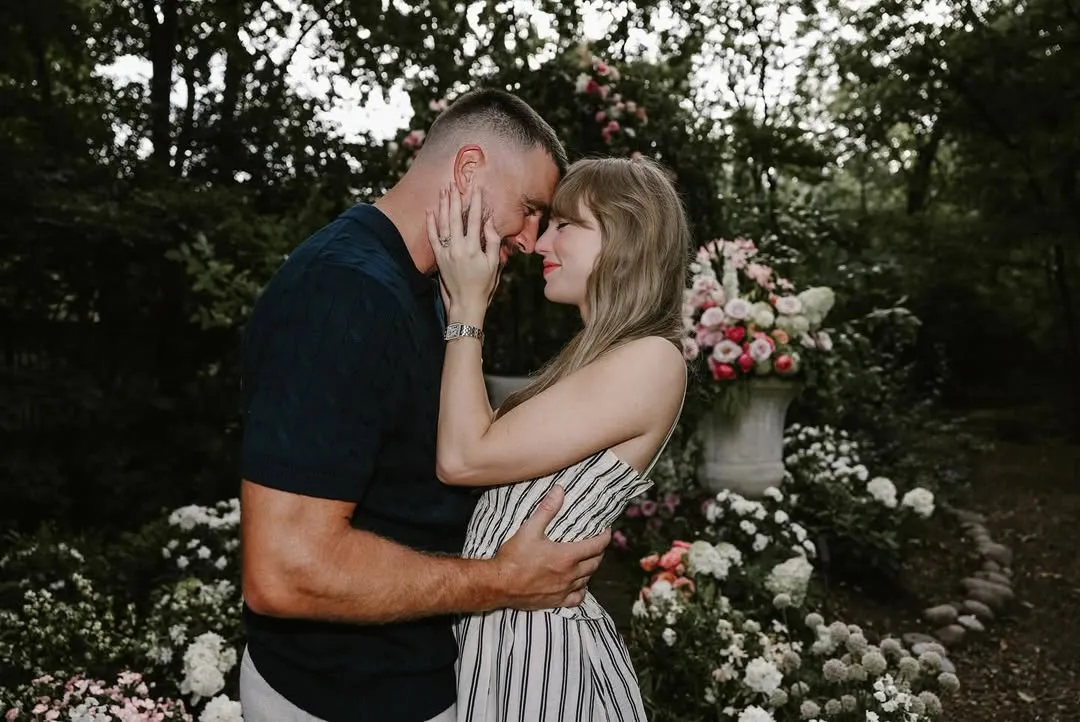 Taylor Swift and Travis Kelce embracing with their foreheads touching in a garden setting.