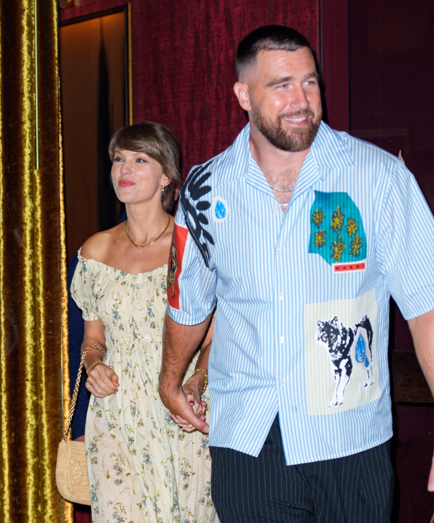 Taylor Swift and Travis Kelce holding hands while leaving a restaurant.