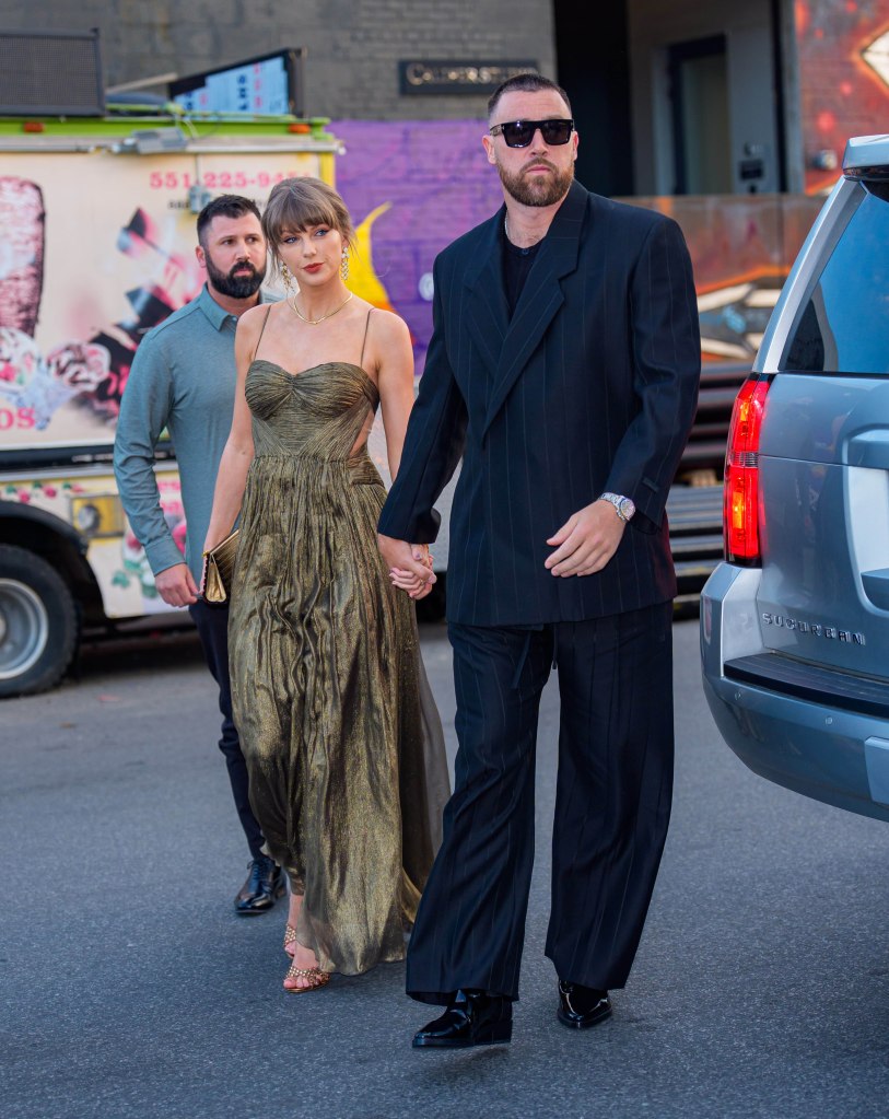 Taylor Swift and Travis Kelce hold hands as they walk with a bodyguard.