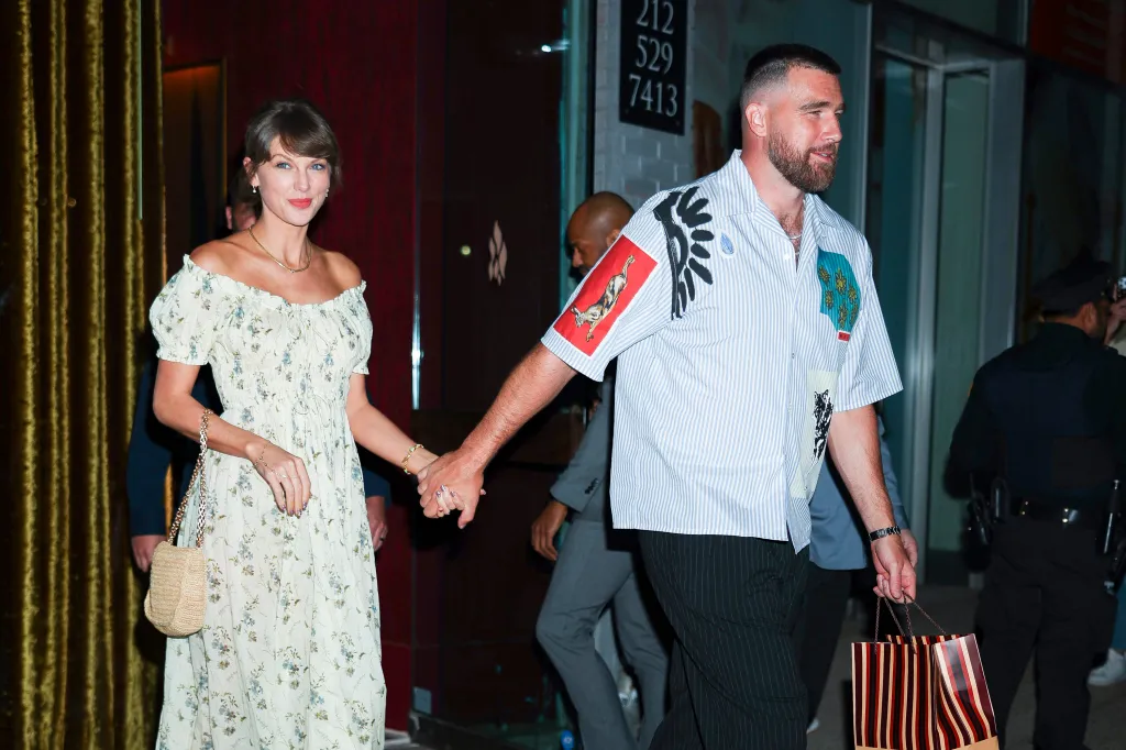 Taylor Swift and Travis Kelce holding hands while walking.