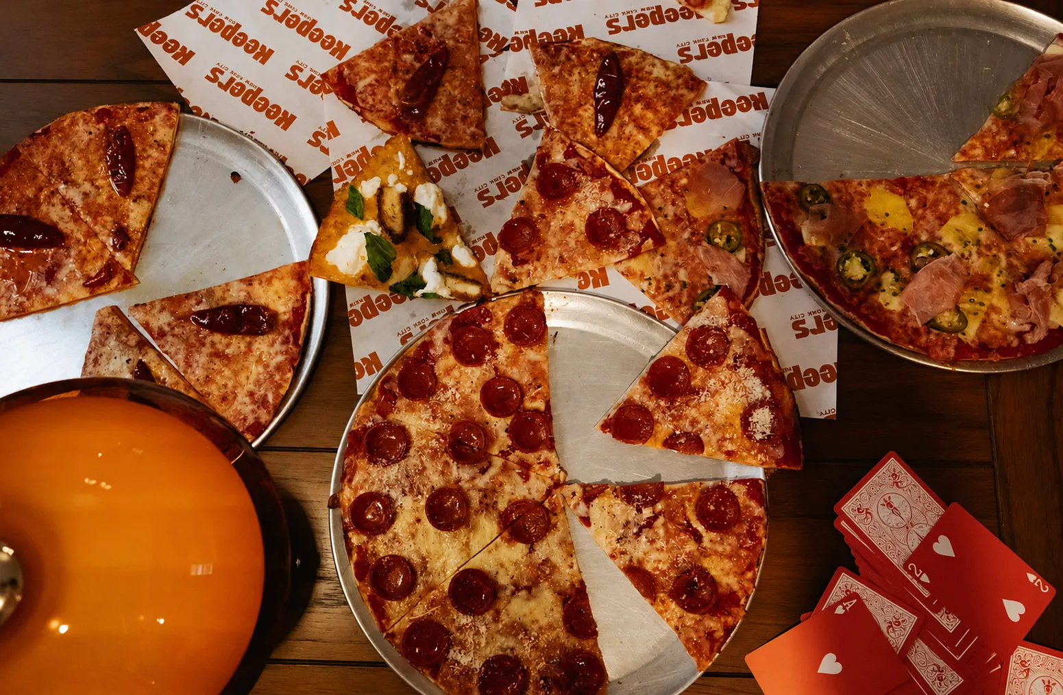 Pizza served on metal trays with red playing cards.