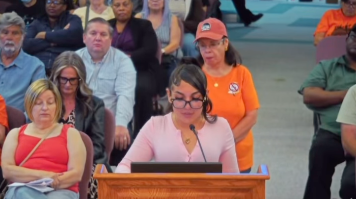 Teen activist Sadie speaking at a podium in front of a seated audience.