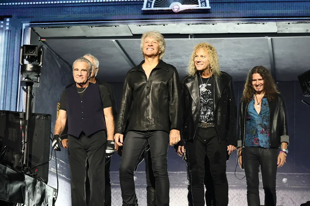 Bon Jovi and band members (Tico Torres, John Shanks, Jon Bon Jovi, David Bryan, Everett Bradley, and Phil X) standing on stage.