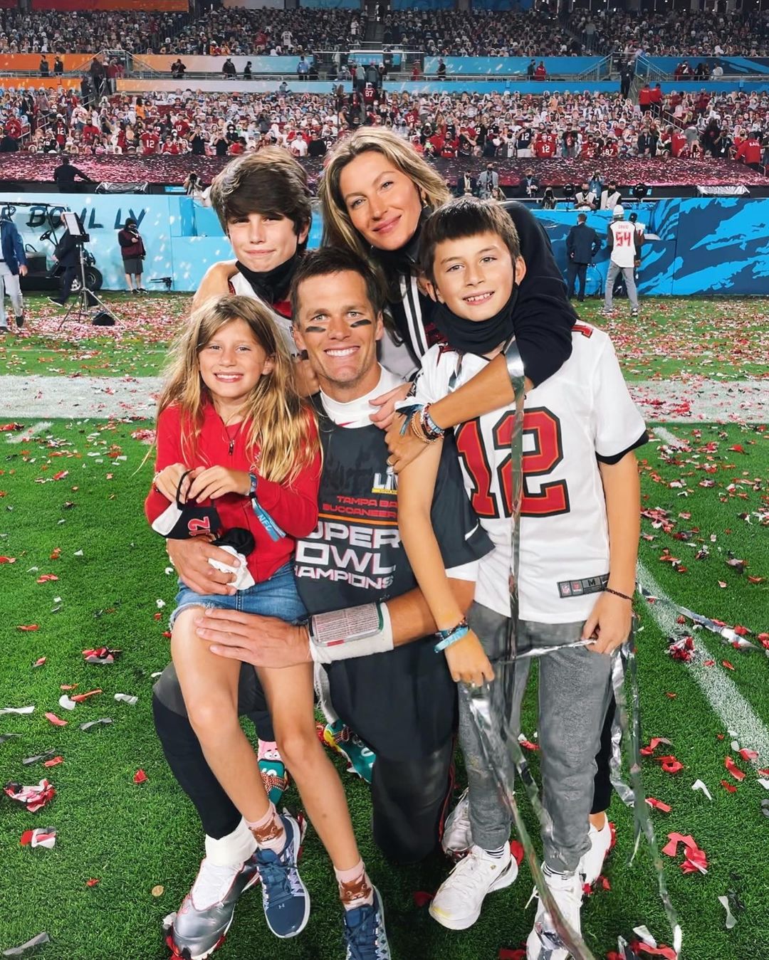 Tom Brady poses with his children and Gisele Bündchen on a confetti-strewn football field.