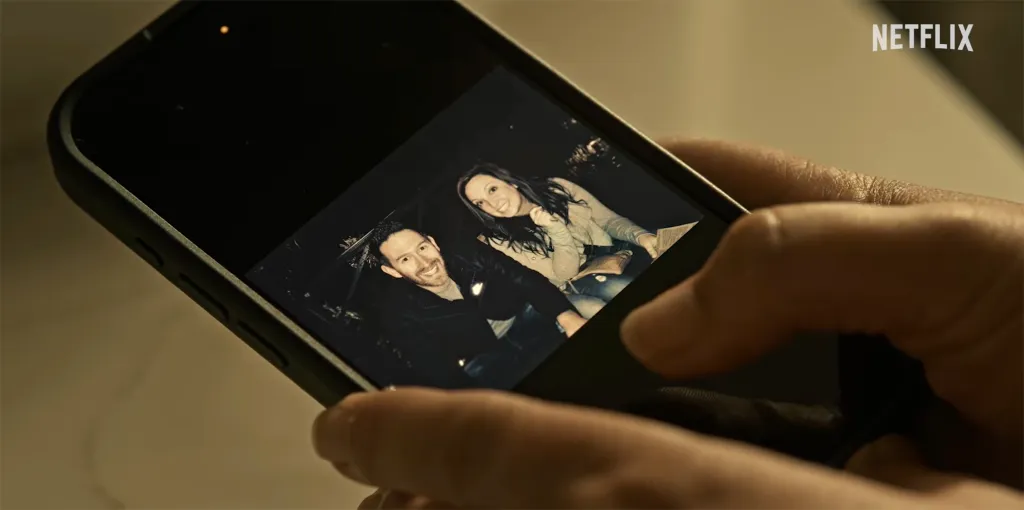 Hands holding a smartphone displaying a photo of a smiling man and woman.