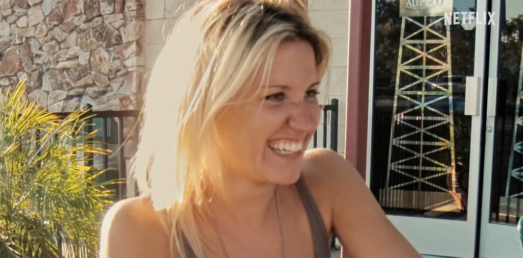 A smiling blonde woman with light freckles on her nose and cheeks.
