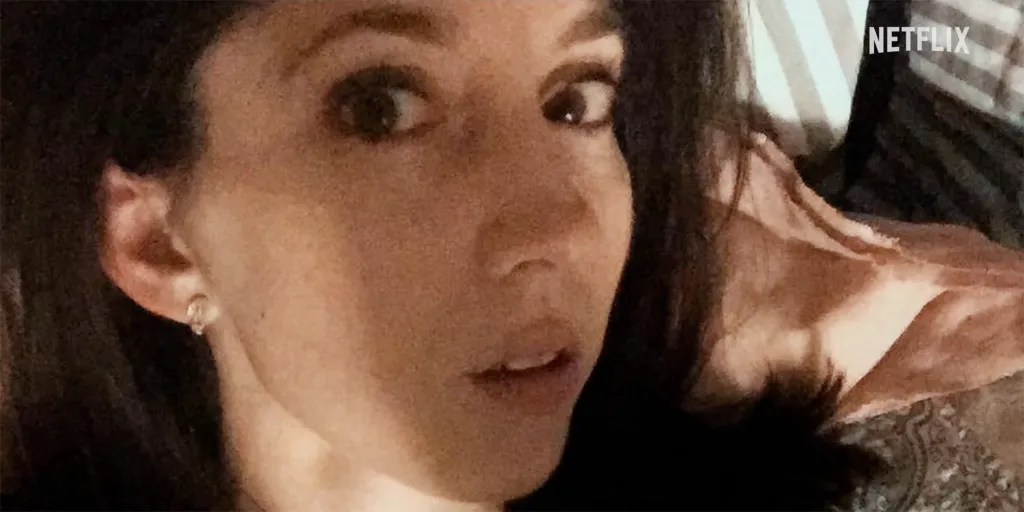 A young woman with wide eyes looks at the camera.