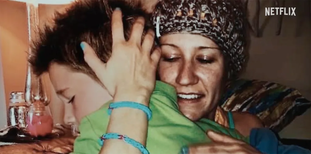 A woman with a patterned beanie embraces a young boy.