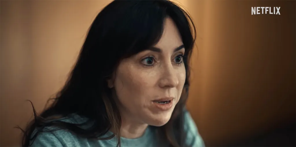 A woman with dark hair and wide eyes speaks.