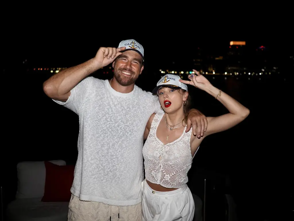 Travis Kelce and Taylor Swift wearing matching "Captain" and "First Mate" hats.