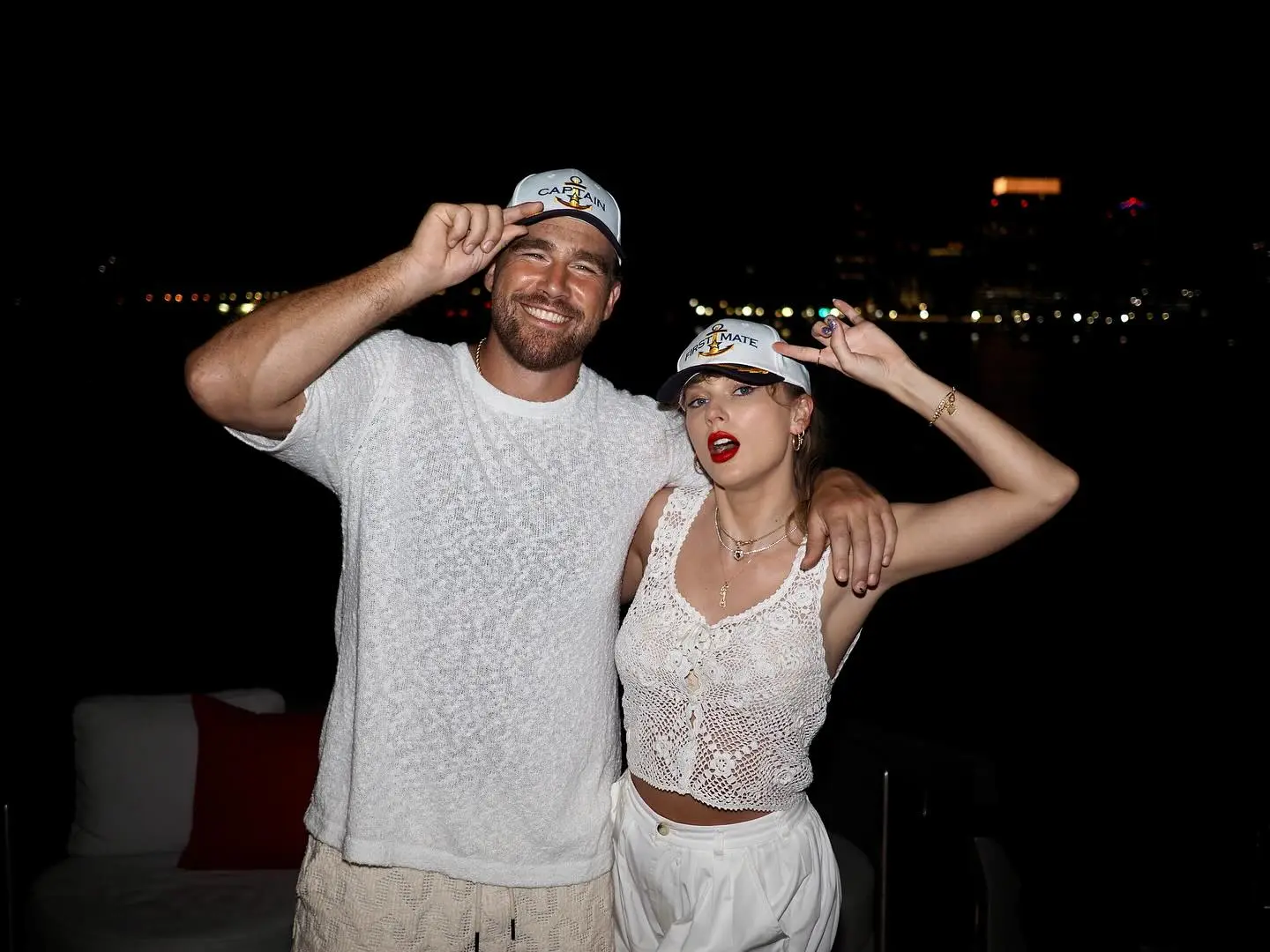 Travis Kelce and Taylor Swift wearing "Captain" and "First Mate" hats, respectively.
