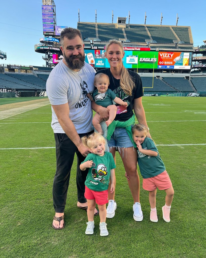 Jason and Kylie Kelce with their three daughters on a football field.