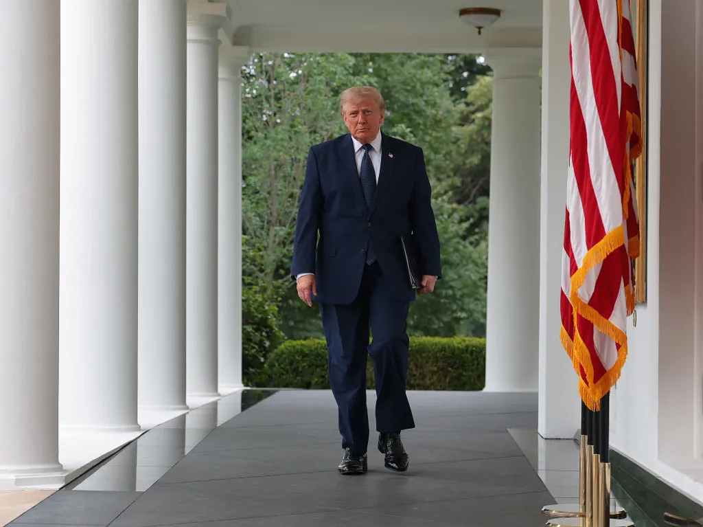 President Trump walks through the White House colonnade to a Rose Garden Club luncheon.