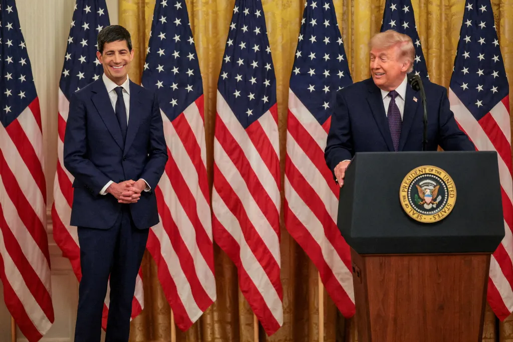 President Donald Trump speaks from a podium with the presidential seal, next to Kevin Warsh, during a swearing-in ceremony.