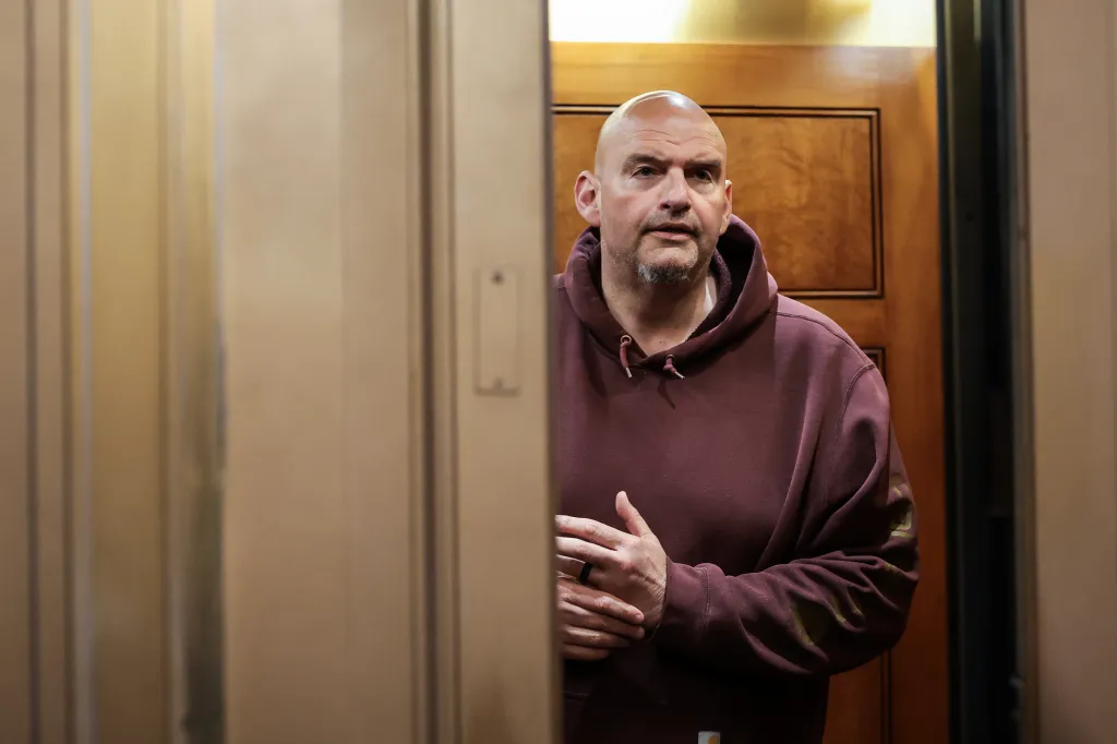 U.S. Senator John Fetterman in a maroon hoodie riding an elevator.