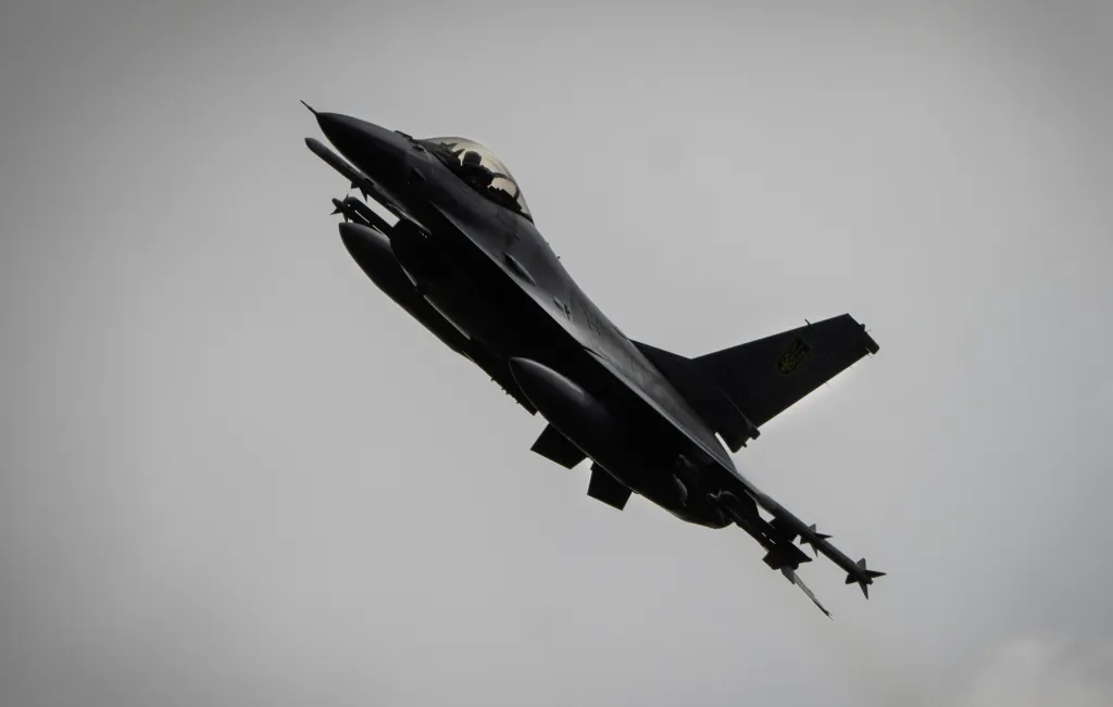 A Ukrainian Air Force F-16 fighter jet flying against a cloudy sky.
